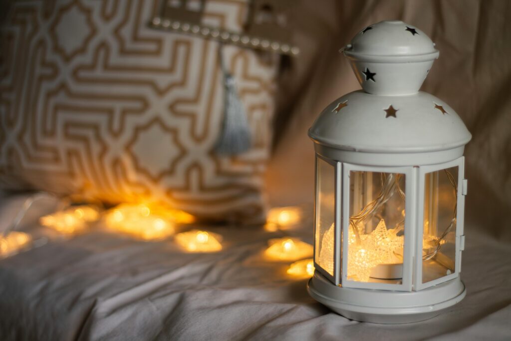White lantern and patterned pillow with soft ambient lighting creating a cozy atmosphere.