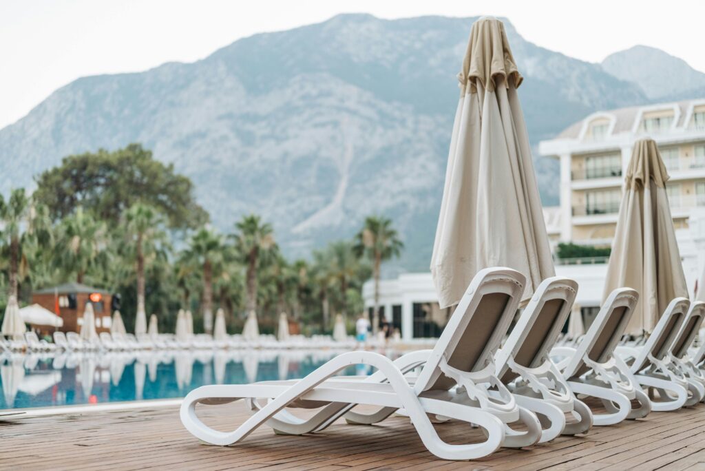 Relax by the pool with sun loungers at a luxury mountain resort featuring palm trees for a perfect summer escape.